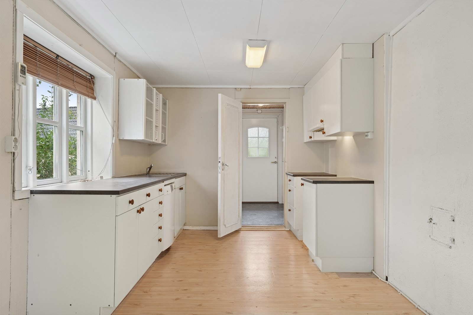 Kjøkkenet har hvite glatte fronter og en benkeplate av laminat. Galleribilde