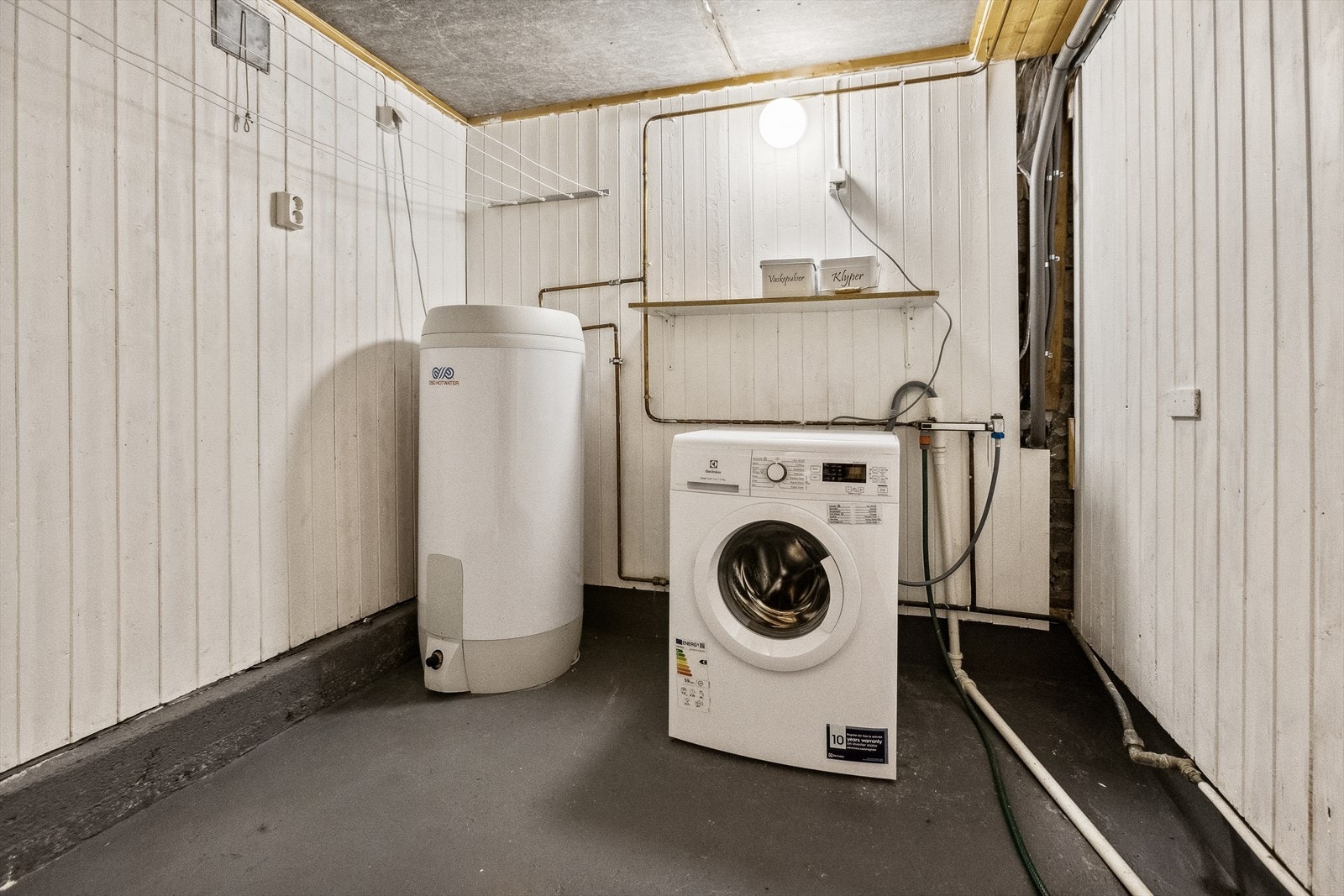 I kjelleren er det et eldre vaskerom med varmtvannsbereder og opplegg for vaskemaskin. Galleribilde