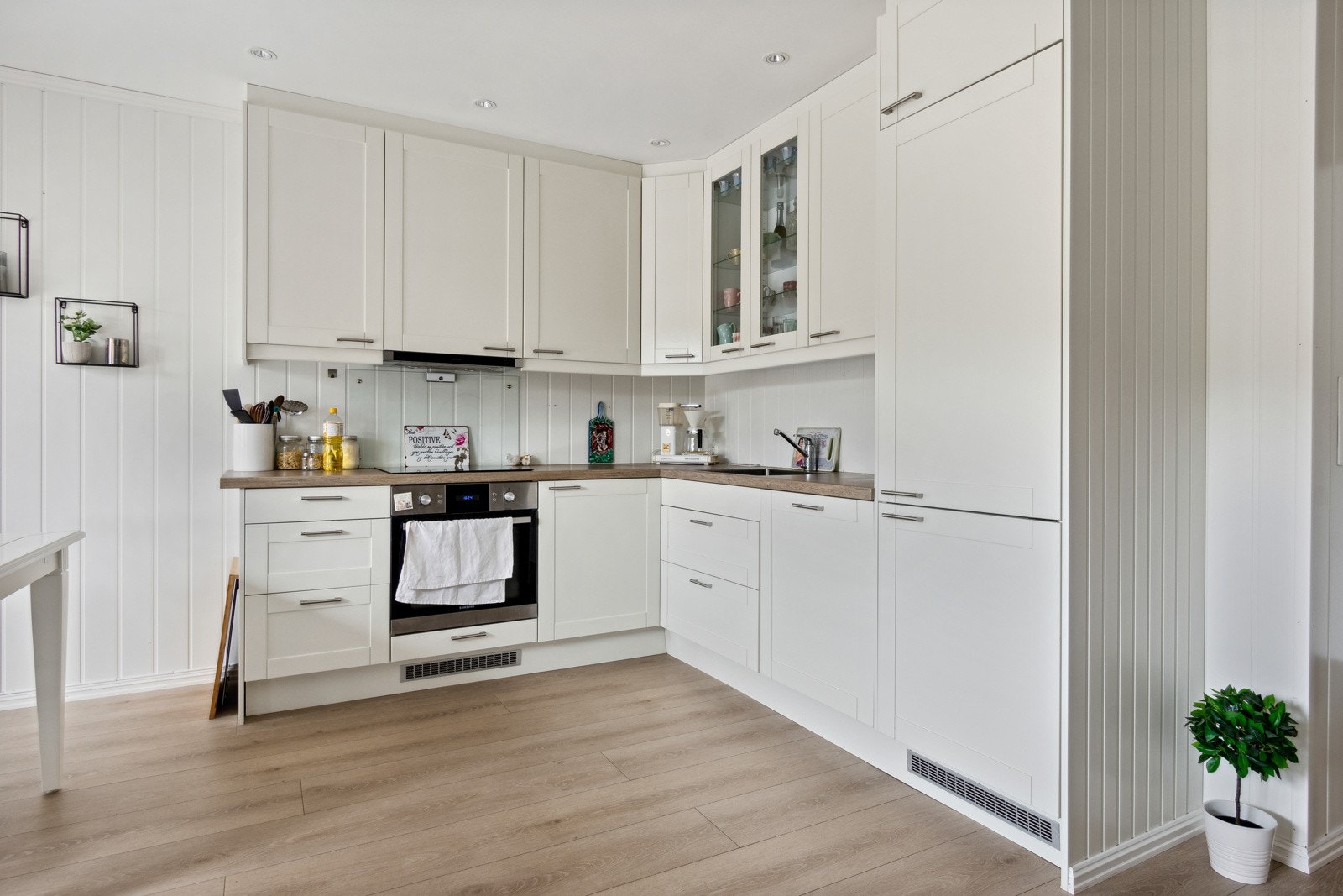 Pent kjøkken med takhøye skap og integrerte hvitevarer. Galleribilde