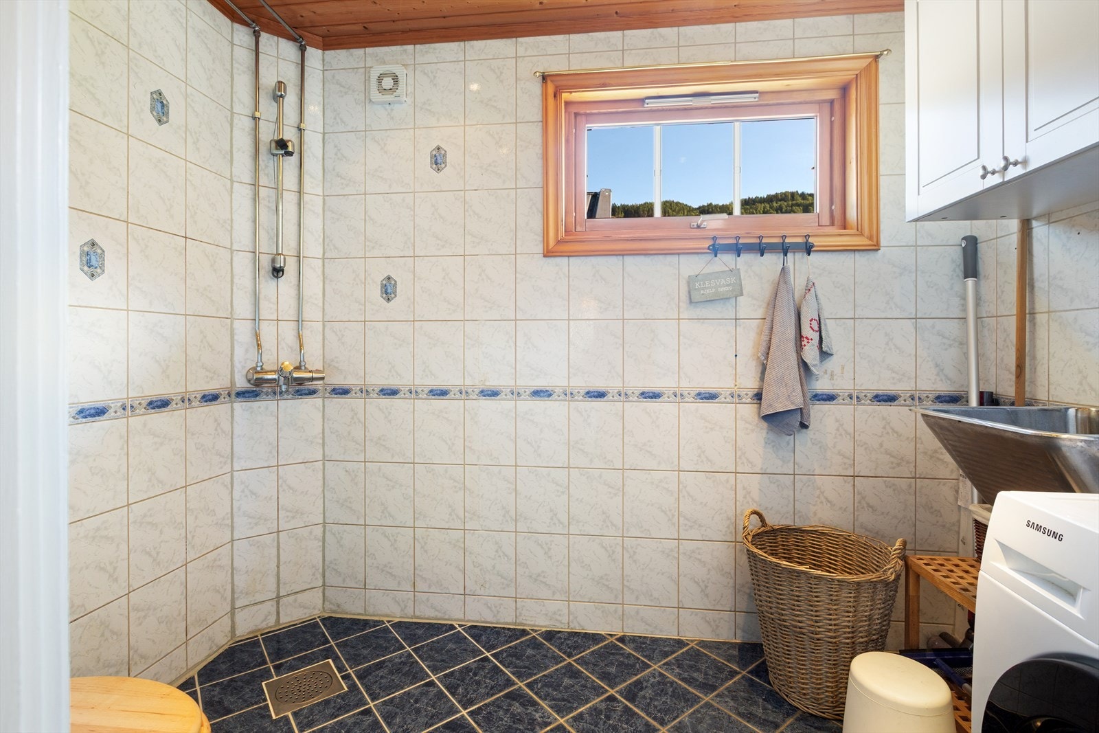 Det som tidligere var bad, har nå blitt et praktisk vaskerom med flislagte vegger og flislagt gulv med varmekabler. På vaskerommet er det dusj på vegg, gulvmontert toalett, stålkum, skapinnredning og opplegg for vaskemaskin. Mekanisk vifte i yttervegg. Galleribilde