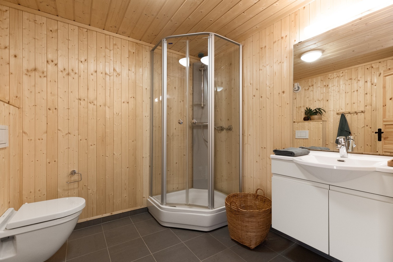 Bad to har en innredning med heldekkende servant, vegghengt toalett og dusjkabinett Galleribilde