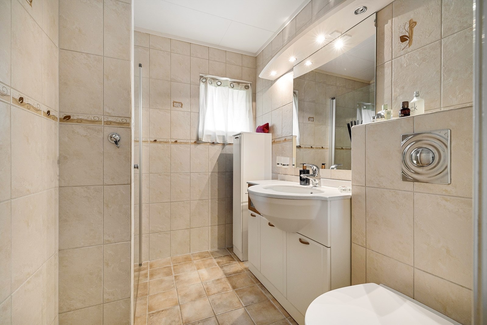 Pent flislagt bad med gulvvarme. Badet er innredet med servant i baderomsinnredning, dusjhjørne og vegghengt toalett. Galleribilde