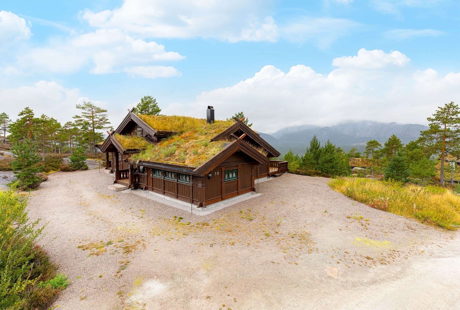 En tradisjonelt bygd hytte med torvtak og vakre utskjæringer, som passer godt inn i landskapet og har et autentisk preg. Galleribilde