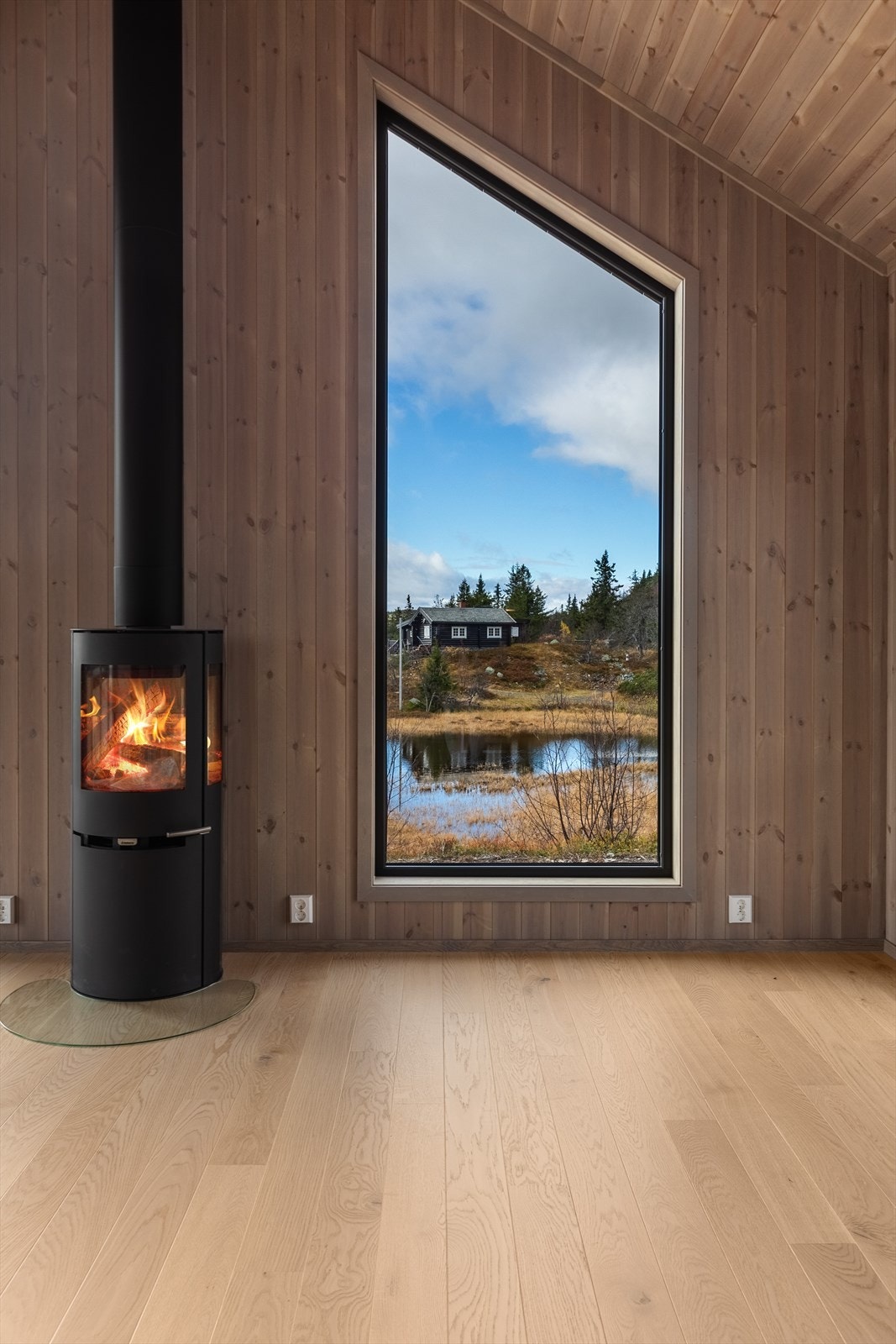 Ovnen er sentralt plassert slik at synet av peisflammene kan nytes i hele rommet. Fra stuen er det også utgang til terrassen og videre ut i terrenget. Galleribilde