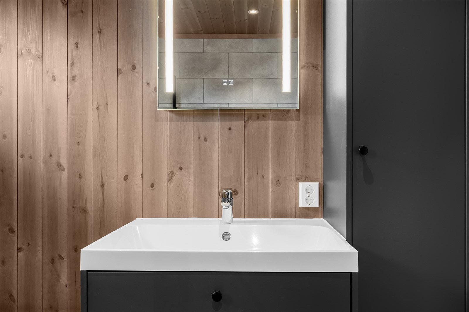 Badet har stilren innredning av typen "Godmorgen" med heldekkende servantplate, store skuffer i servantskapet og et høyskap. Speil med belysning. Galleribilde