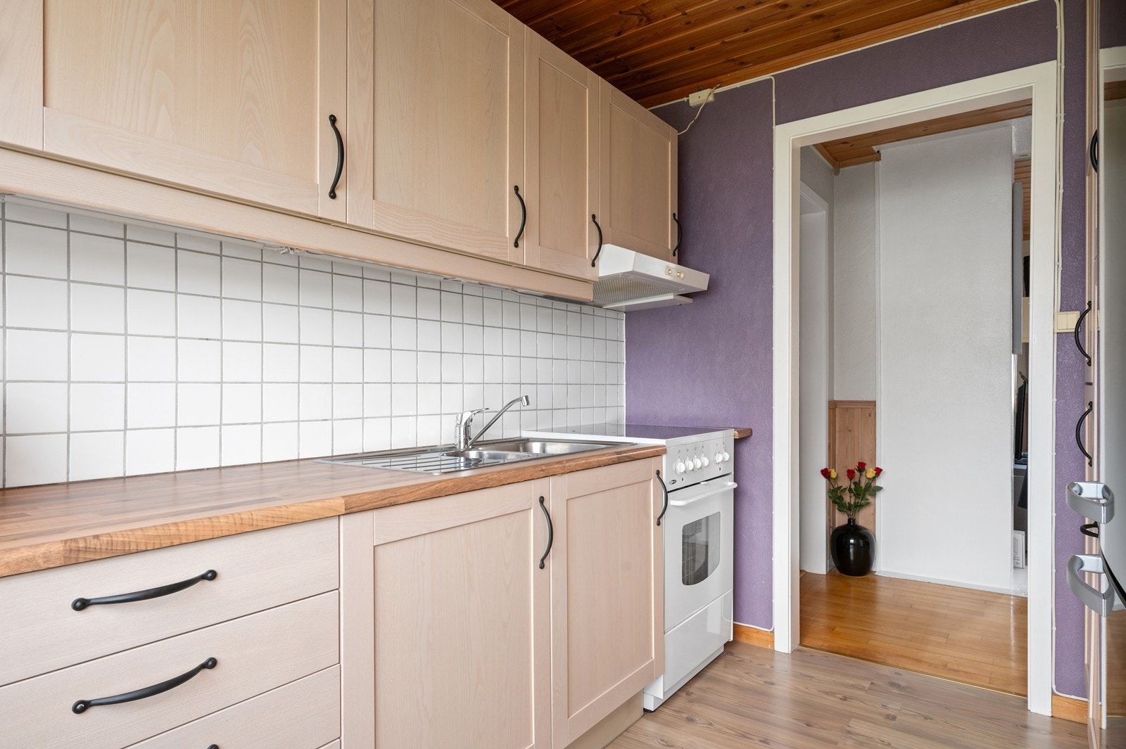 Det er frittstående hvitevarer og det er flislagt mellom benk og overskap Galleribilde