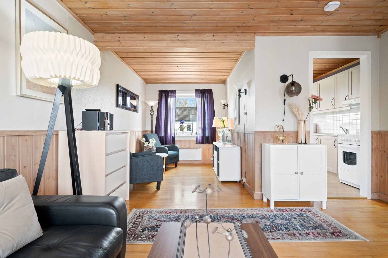 En romslig stue med flere møbleringssoner, og enkel atkomst til kjøkkenet Galleribilde