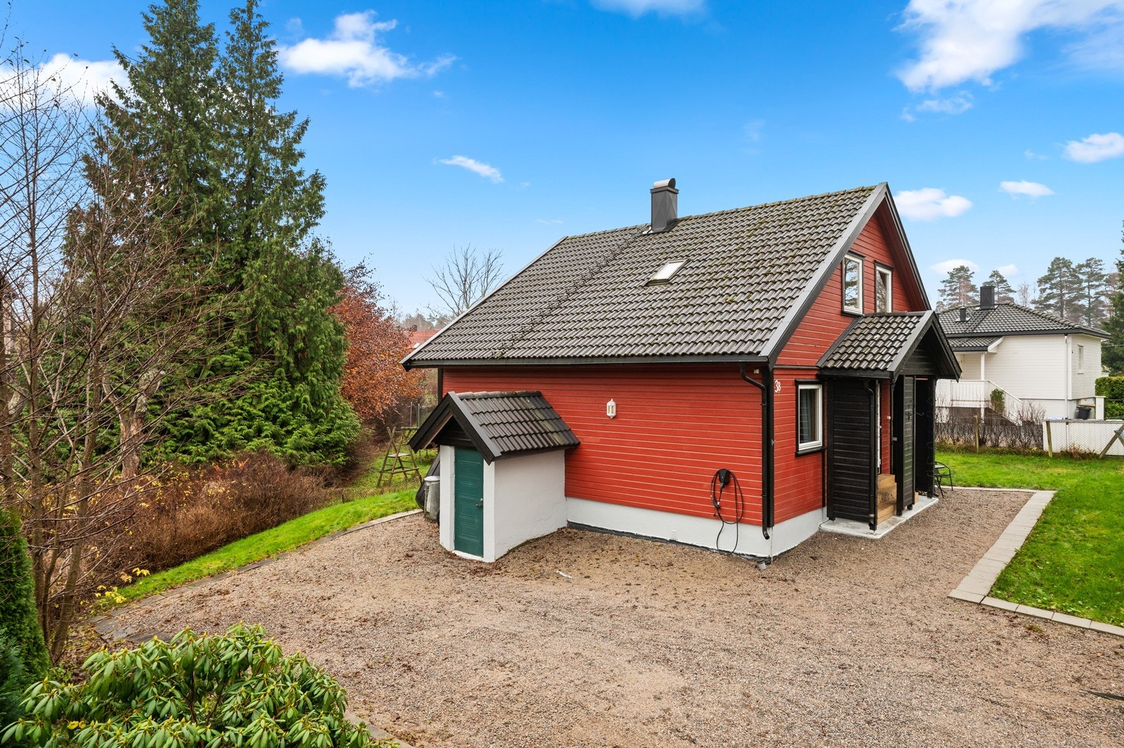 Gruset gårdsplass med god plass til parkering, omkranset av grøntarealer og beplantning. Galleribilde