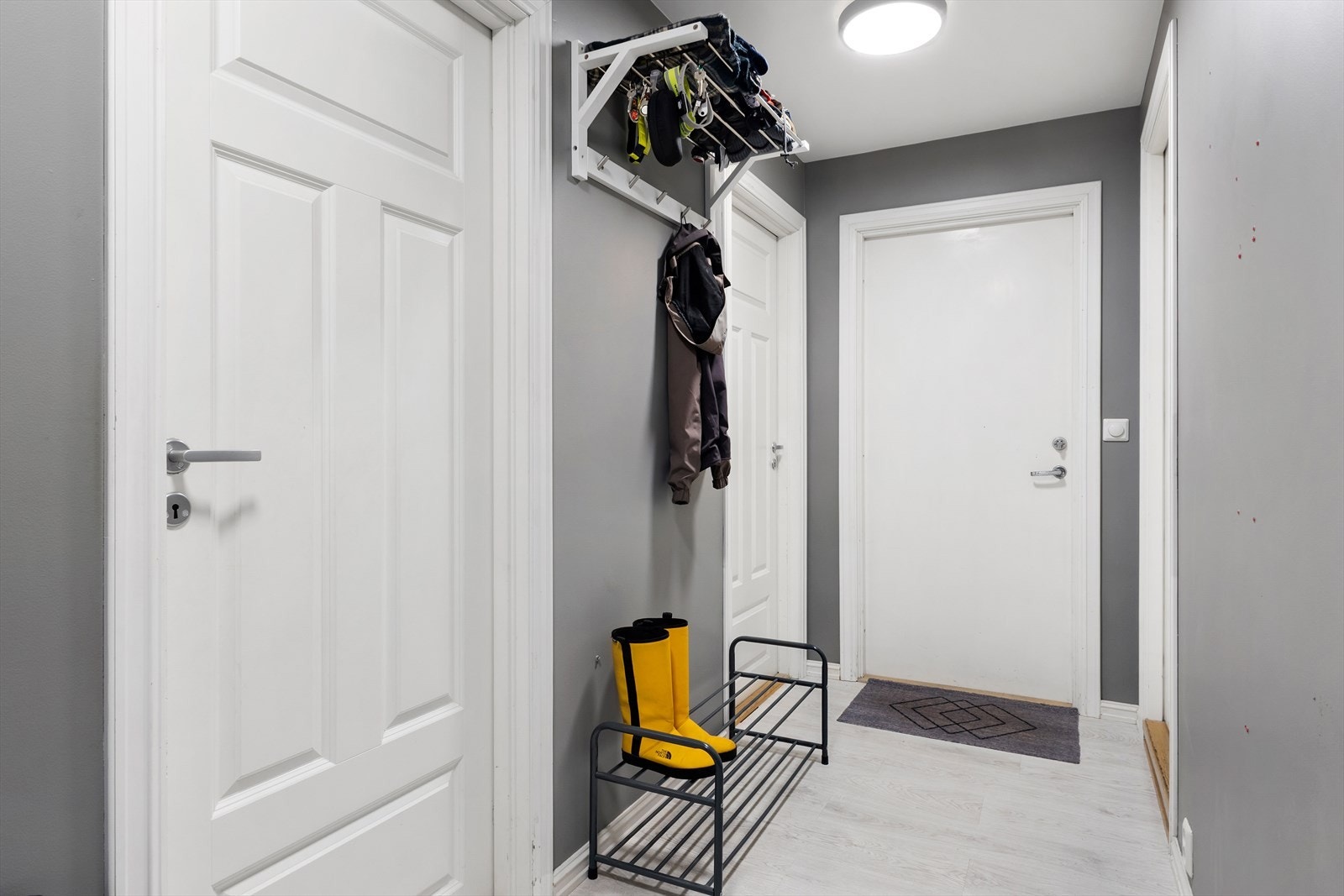 Vi starter i gangen. Den er malt i gråtoner med slette, moderne overflater. Gulvet er lagt med lys laminat. På høyre hånd finner du badet. Galleribilde