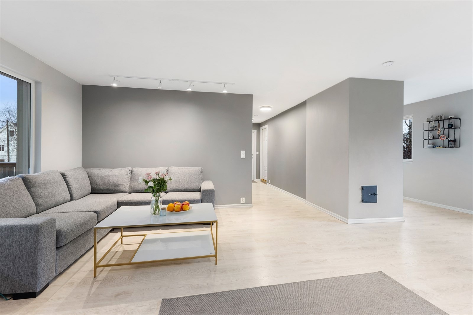 Den lekre gråfargen fra gangen brytes av en lysere tone som strekker seg mot kjøkkenet. Galleribilde