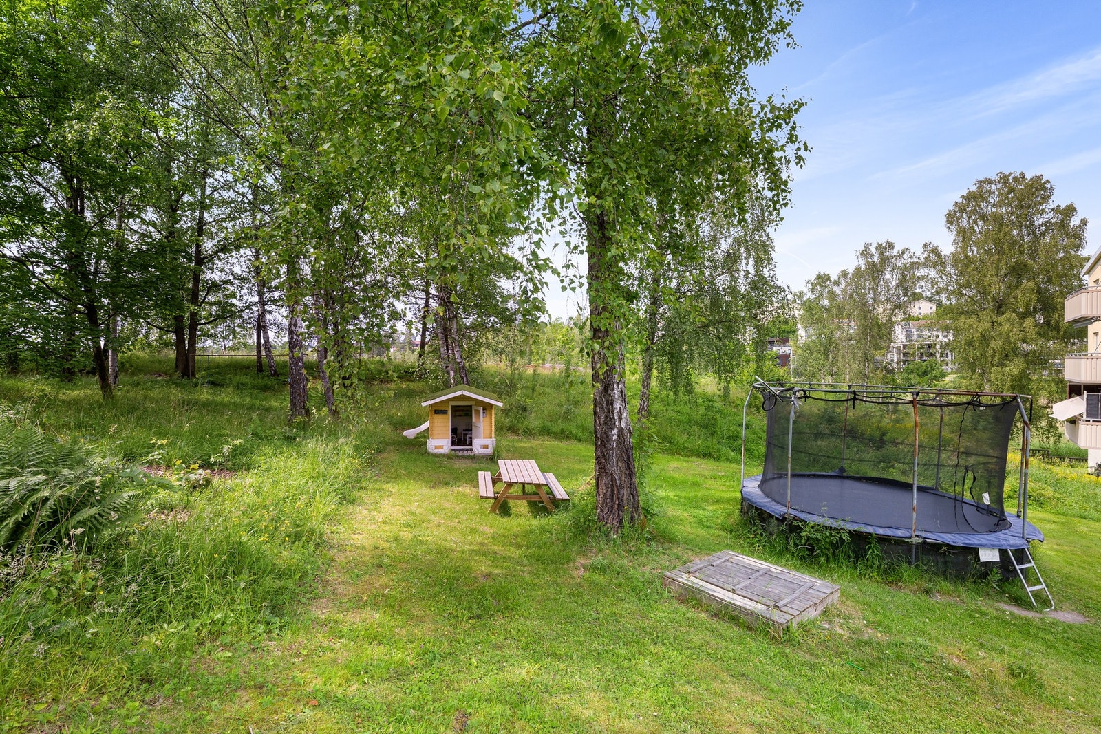 Lekeplass med dukkestue, husker, sandkasse, trampoline og sklie som vedlikeholdes av borettslaget Galleribilde