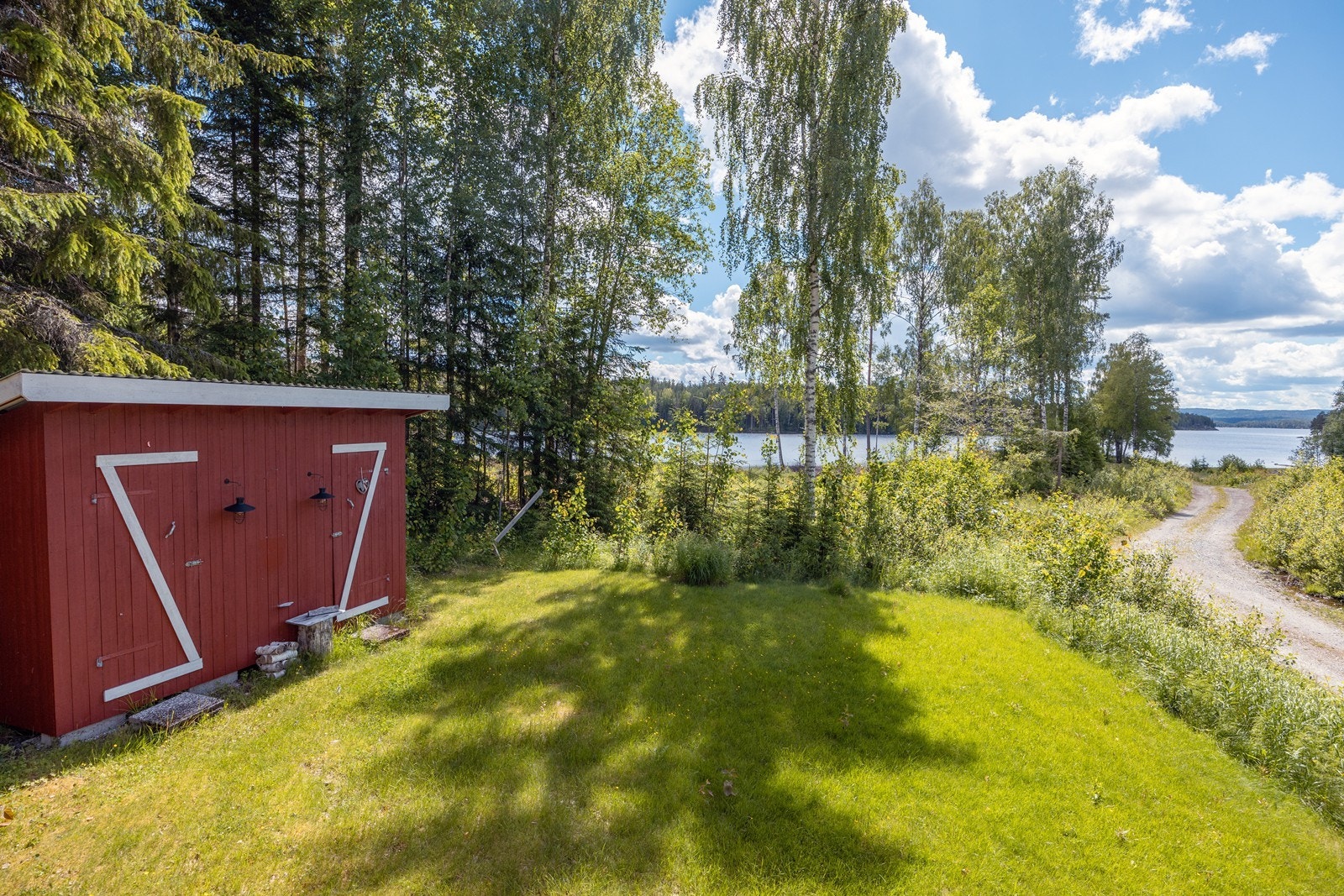 Hage med plen utenfor hytta og uthus. Galleribilde