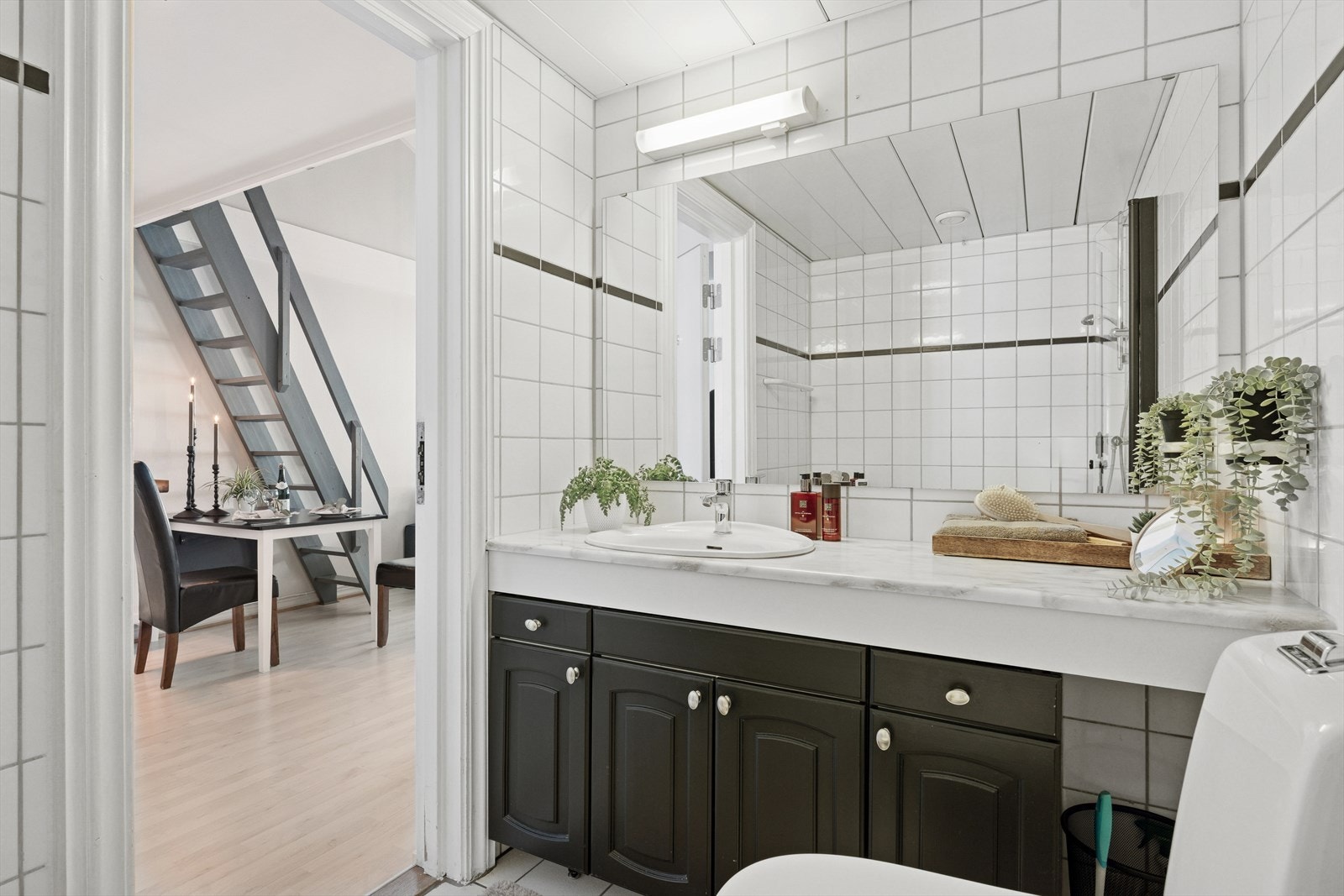 Delikat, flislagt baderom med servant nedfelt i skapinnredning. Galleribilde