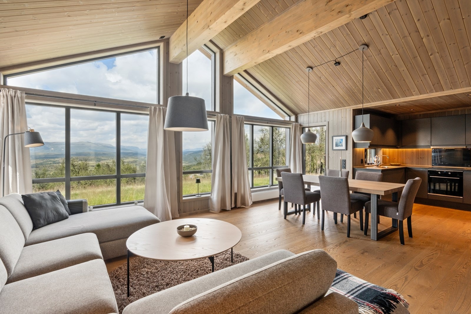 Fronten domineres av høye vinduer som strekker seg helt opp til skråtaket og gir det store oppholdsrommet lys og volum. Galleribilde