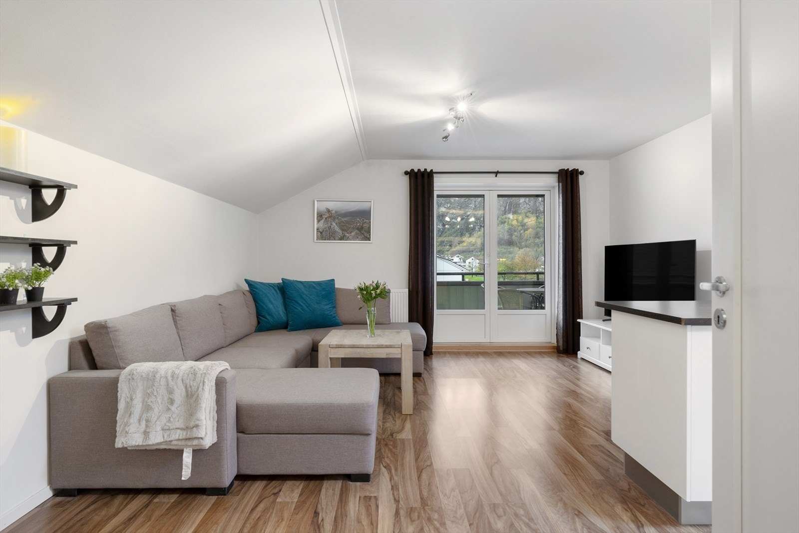 Store vindusflater på balkongdør i stuen gir utsyn mot nærliggende grøntområder. Galleribilde