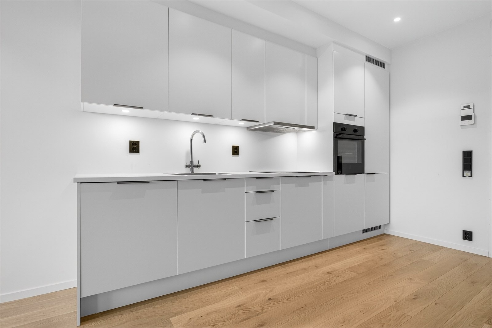 Kjøkkeninnredning med glatte fronter gir et ryddig og moderne uttrykk. Integrerte hvitevarer samler kjøkkensonen. Galleribilde