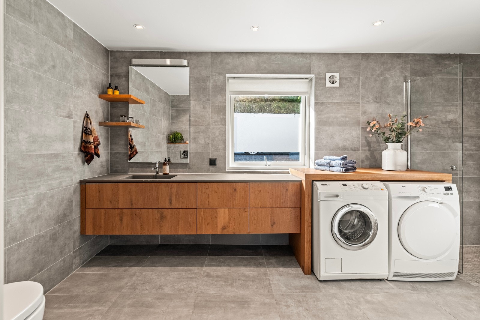 Her får du en smart kombinasjon av bad og vaskerom, med rikelig plass til både oppbevaring og klesvask. Galleribilde