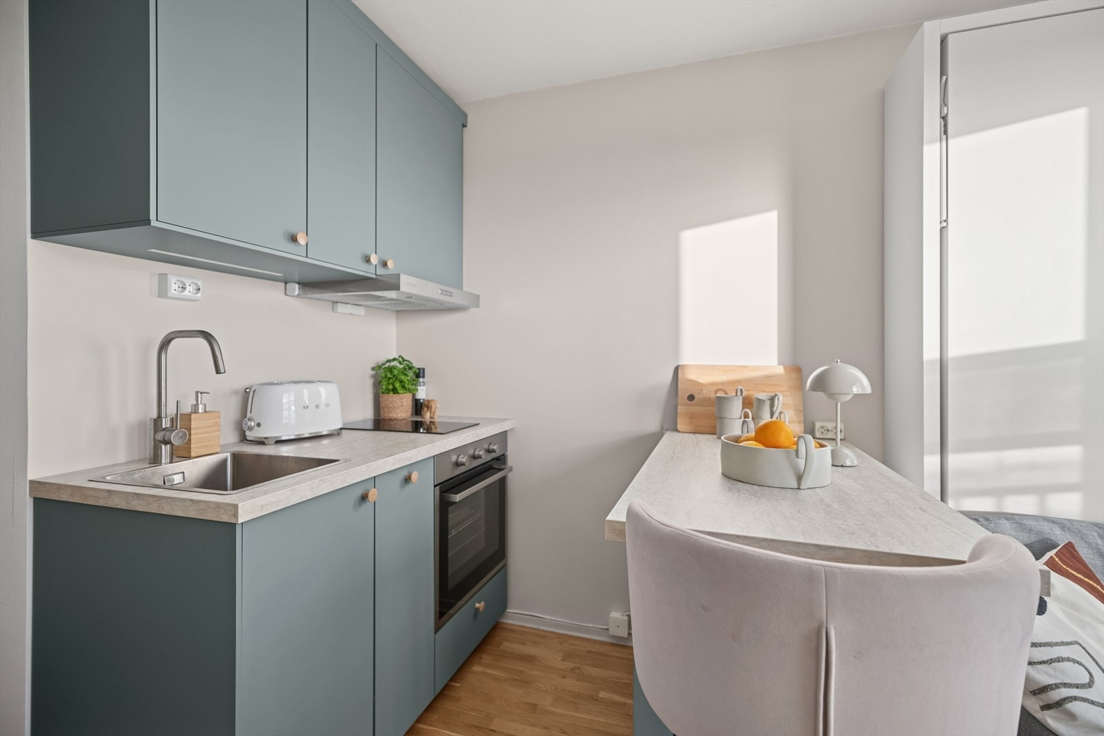 Alt av hvitevarer er elegant integrert - platetopp, stekeovn, kjøleskap og ventilator - som gir kjøkkenet et helhetlig, stilrent og moderne preg. Løsningen skaper rene linjer og en funksjonell arbeidsflate som både ser bra ut og er enkel å holde ryddig. Galleribilde