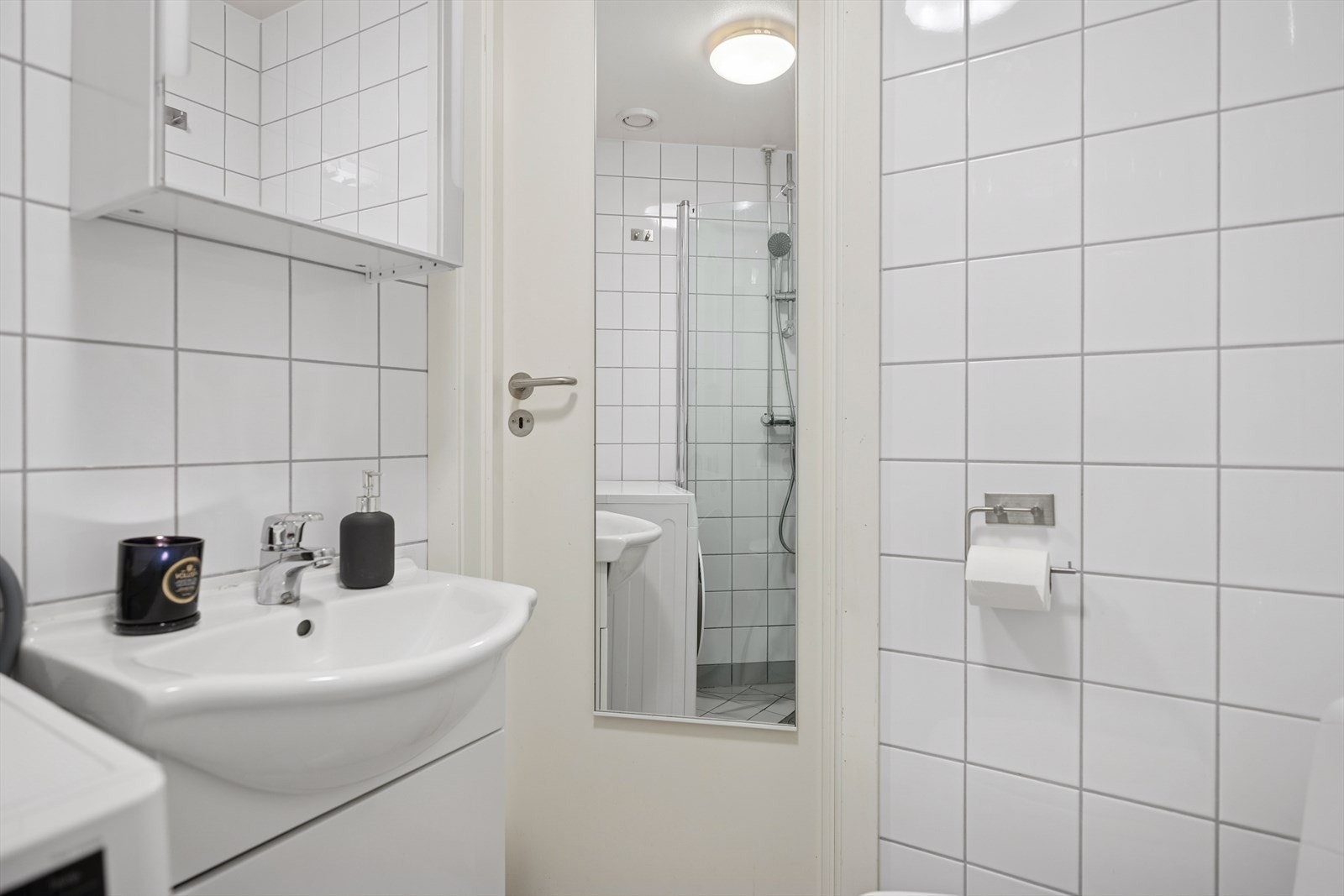 Badet har dusj med innfellbare glassdører, servant med underskap, veggskap og speil, samt opplegg for vaskemaskin. Galleribilde