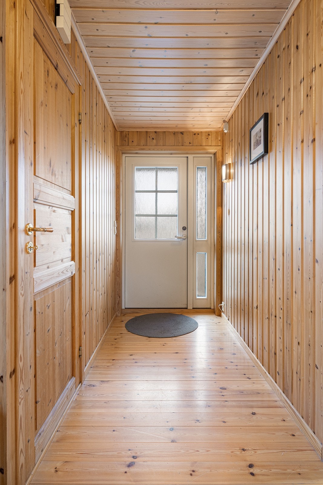 Entréen har naturlig panel på veggene og originalt, lakkert heltregulv. Galleribilde