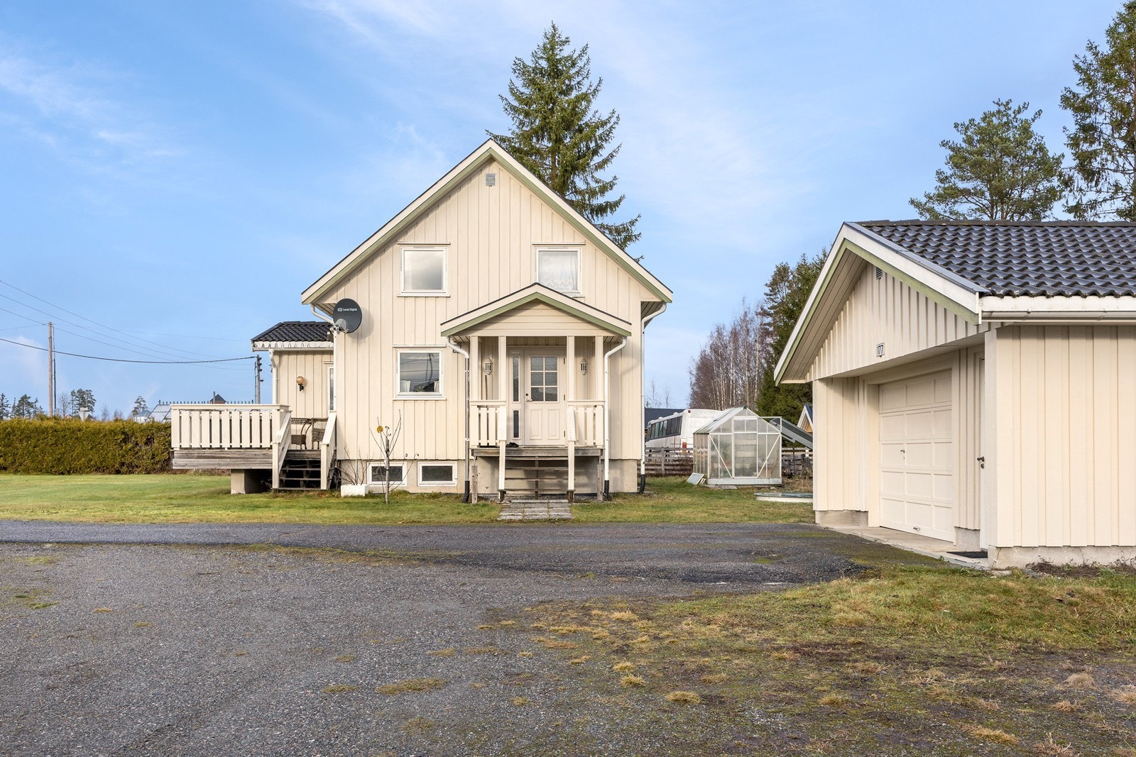 Tomten er opparbeidet med plenarealer, prydbusker, asfaltert innkjørsel og høyreiste trær. Galleribilde