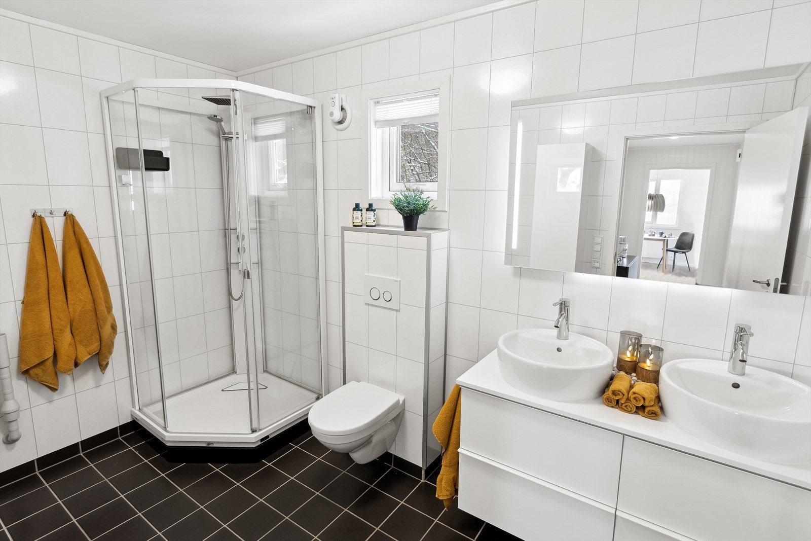 Stort bad med vegghengt toalett, servant med to vasker, speilskap og romslig dusjkabinett. Galleribilde