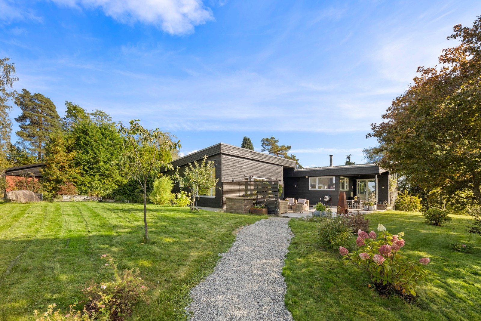 Eiendommen er pent opparbeidet med gressplen og beplantninger. Galleribilde
