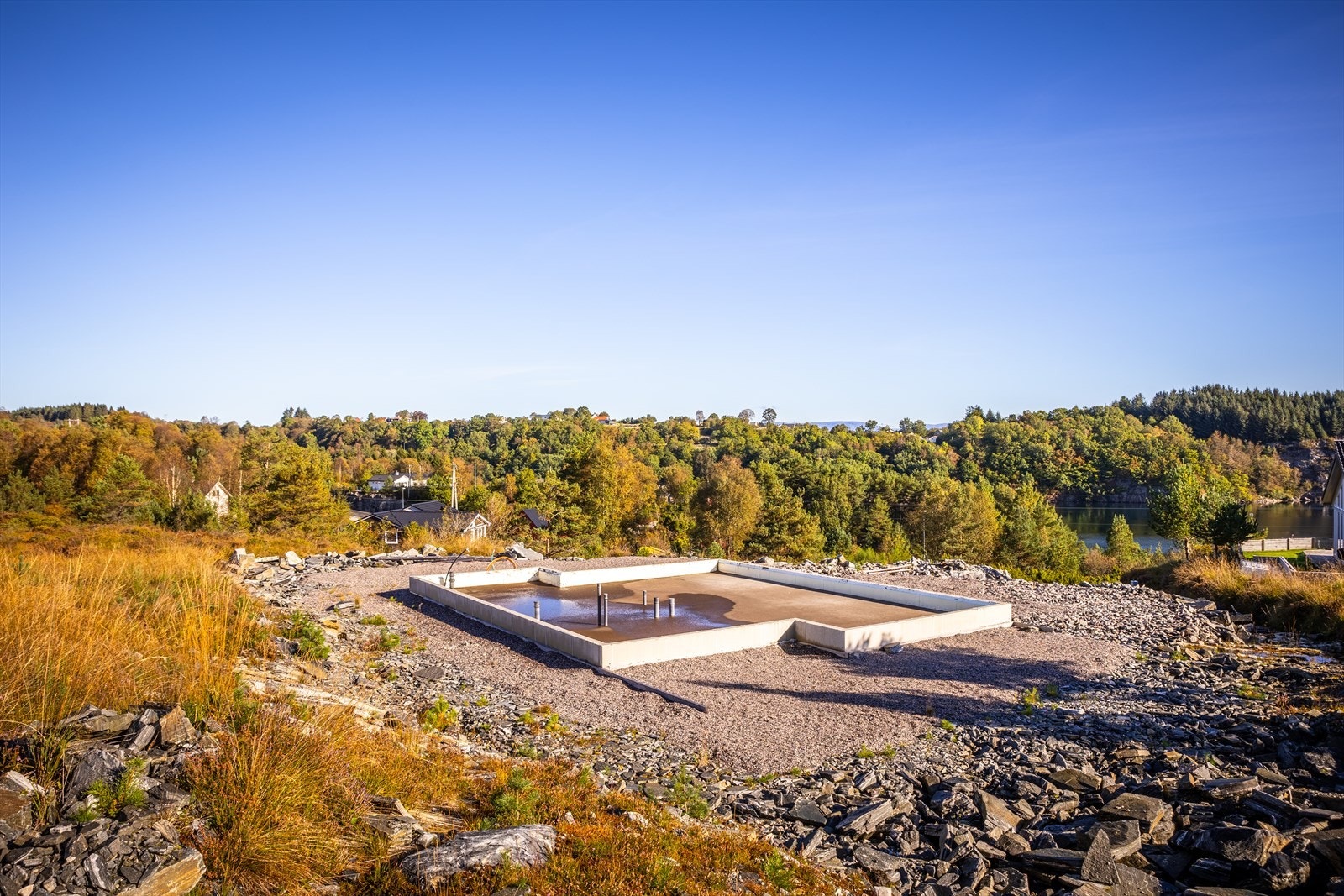 Øverste del av tomten er planert. Det er etablert grunnsåle/grunnmur som er fundamentert på komprimert masse. Vann, avløp, strøm og fiber er lagt inn til grunnsålen. Galleribilde
