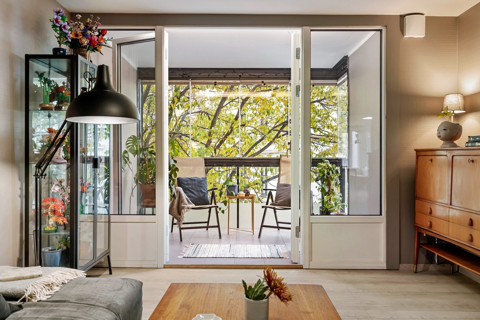 Dobbeltdørene fører ut til en innglasset balkong som blir en naturlig forlengelse av oppholdsrommet - perfekt for rolige morgener med kaffe eller sene kvelder Galleribilde