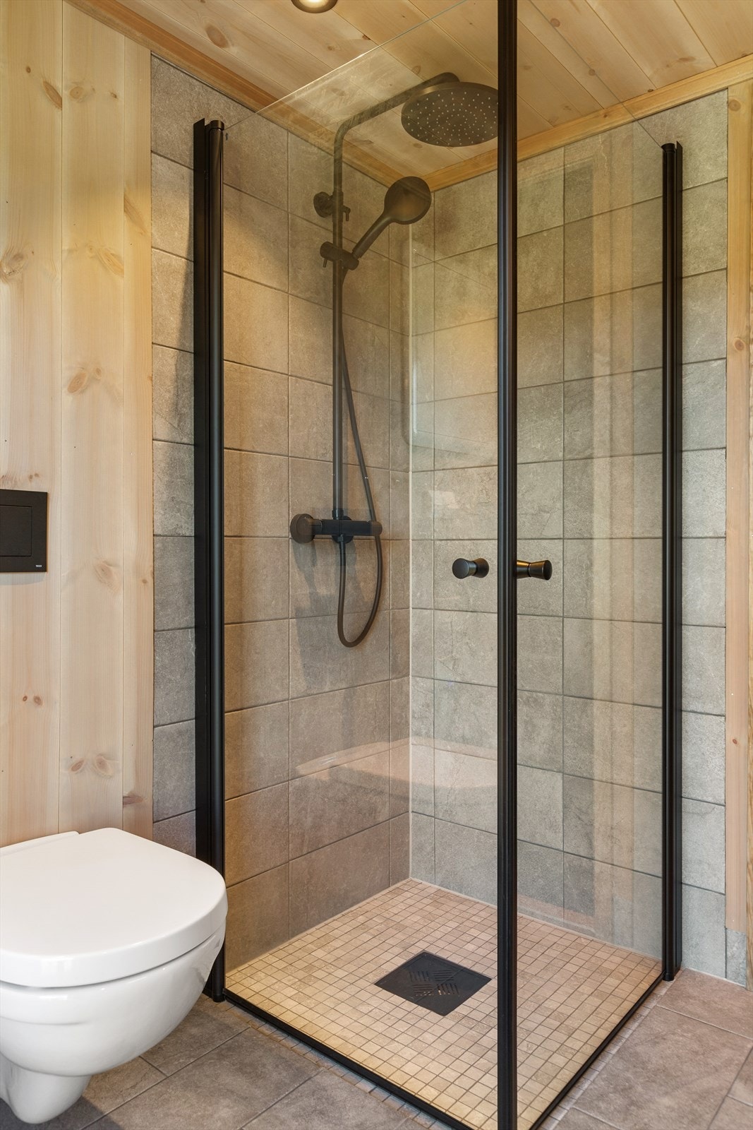 Flislagt dusjhjørne med innfellbare glassdører, noe som er både pent og praktisk. På badet er det også vegghengt toalett med innebygd sisterne, vifte og varmtvannsbereder. Opplegg for vaskemaskin. Galleribilde