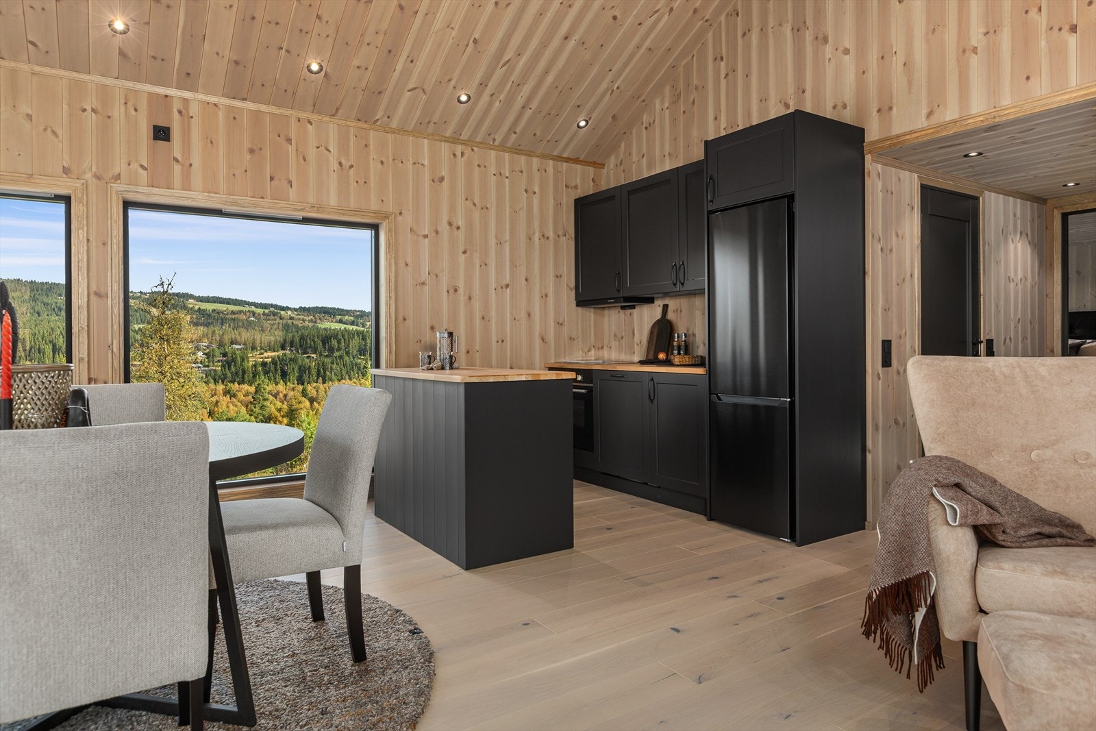 Kjøkkeninnredningen er i heltre, malt i fargen "Dempet Sort". Den har bra med skap- og benkeplass, og integrerte hvitevarer som stekeovn, koketopp, ventilator og oppvaskmaskin, samt frittstående kjøl-/fryseskap, alle med stilige, mørke fronter. Galleribilde