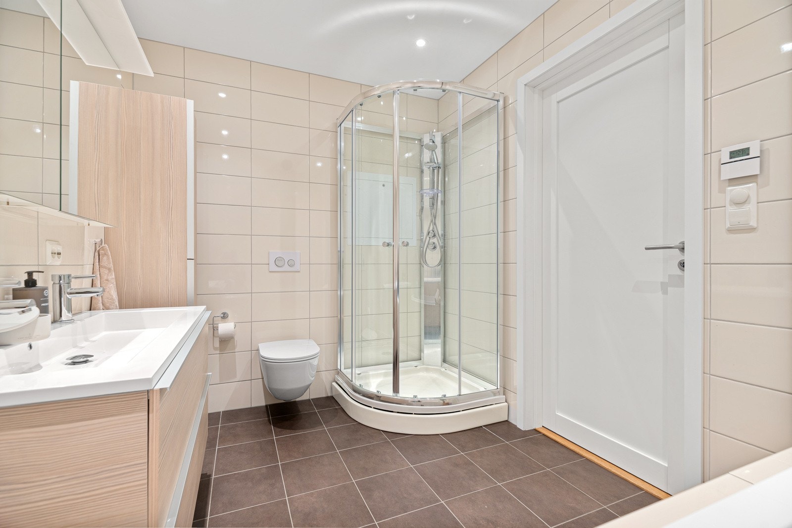 Pent flislagt og romslig baderom med boblebad, Vikingbad dusjkabinett, vegghengt klosett og innholdsrik Fossbad innredning med dobbelvask. Galleribilde