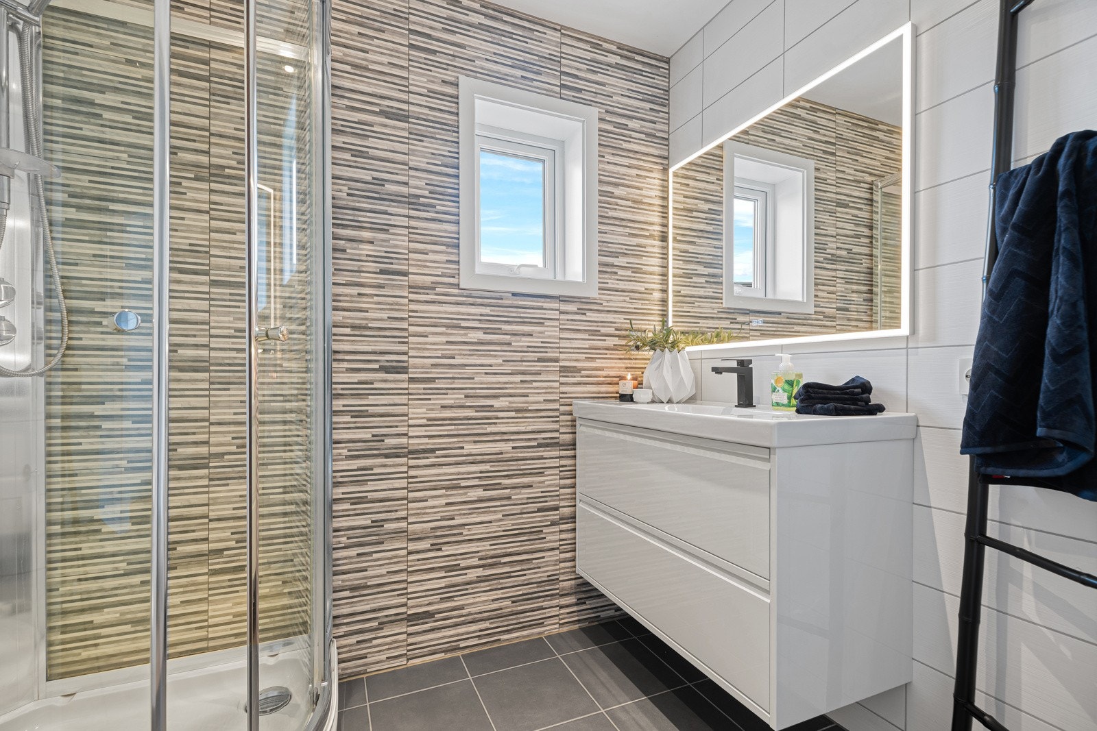 Pent flislagt bad med LED-downligt i praktikantdelen. Ny baderomsinnredning/speil og opplegg for oppvaskmaskin (2025) Vegghengt klosett og Vikingbad dusjkabinett fra byggeår. Galleribilde