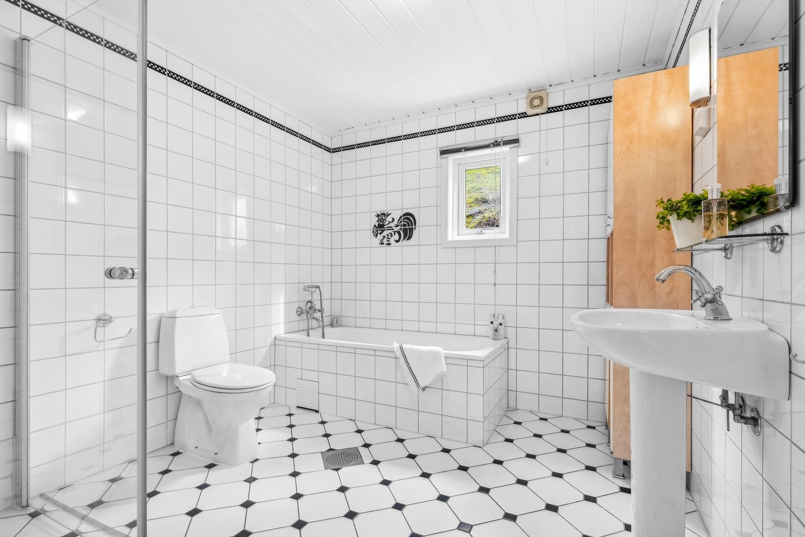 Bad I - Pent flislagt bad innredet med dusjhjørne, badekar, enkel servant, gulvstående toalett, samt høyskap Galleribilde