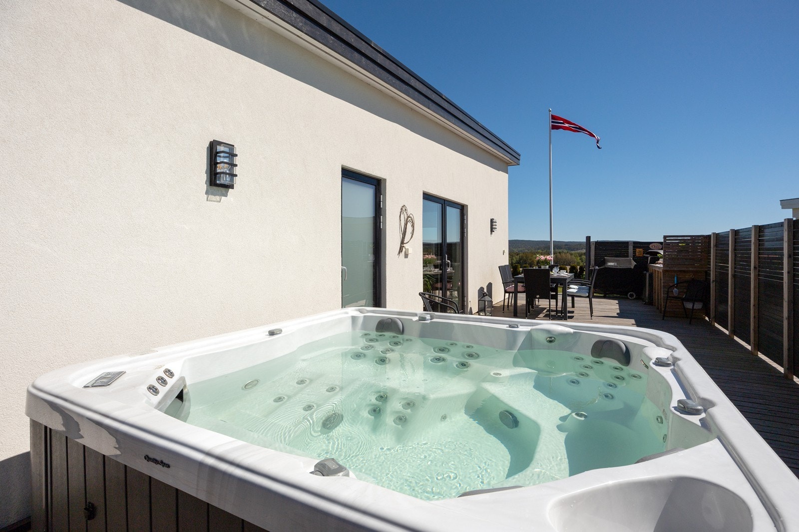 Den sydvendte delen skjermes fint med høye levegger, og den store sonen har både utekjøkken, spiseplass og et herlig jacuzzi. Galleribilde