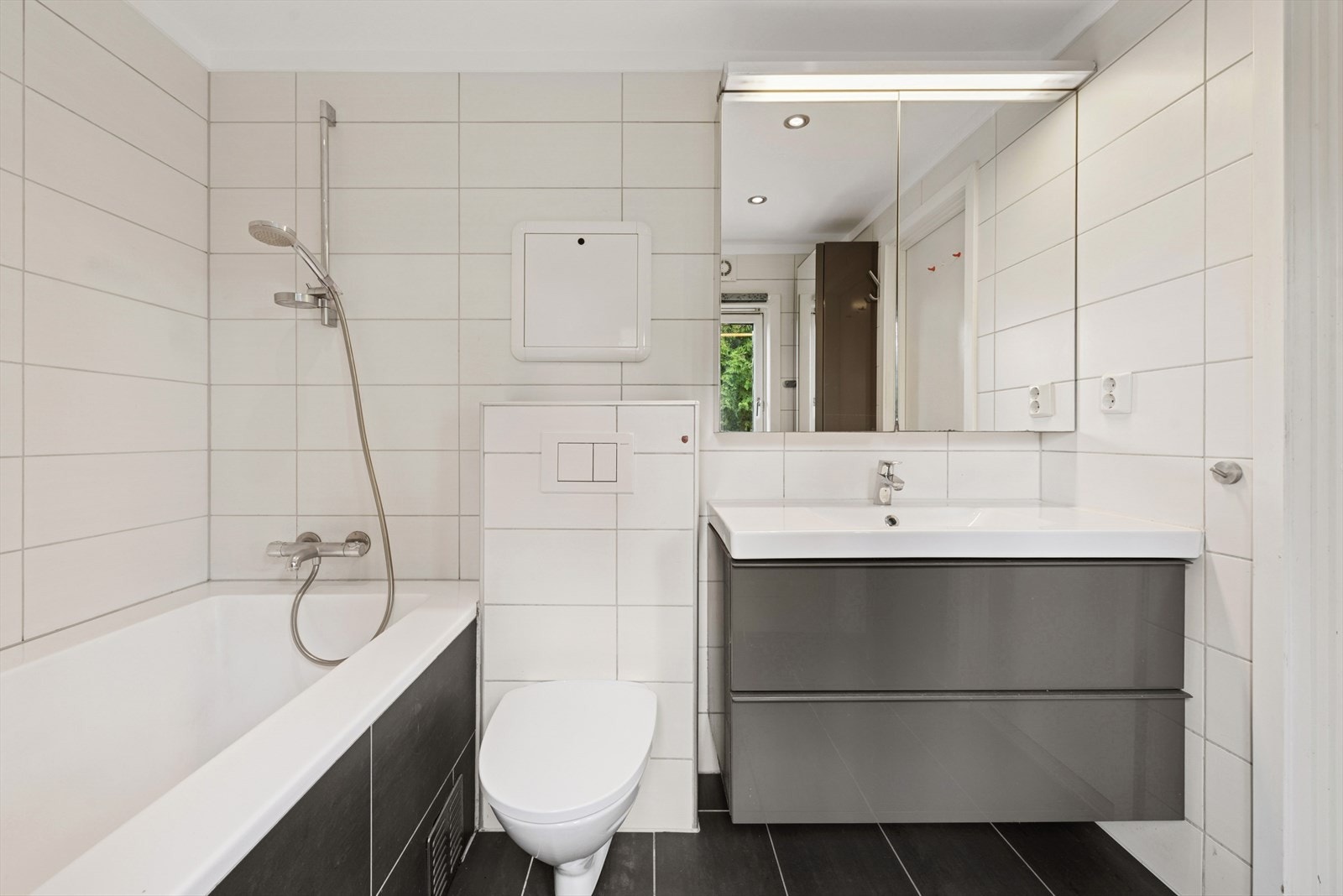 Badet er innredet med servant, veggmontert toalett og badekar. Galleribilde