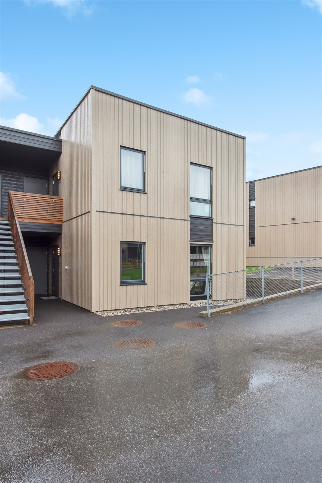 Bygget har en moderne fasade med en kombinasjon av lys og mørk trekledning. Galleribilde