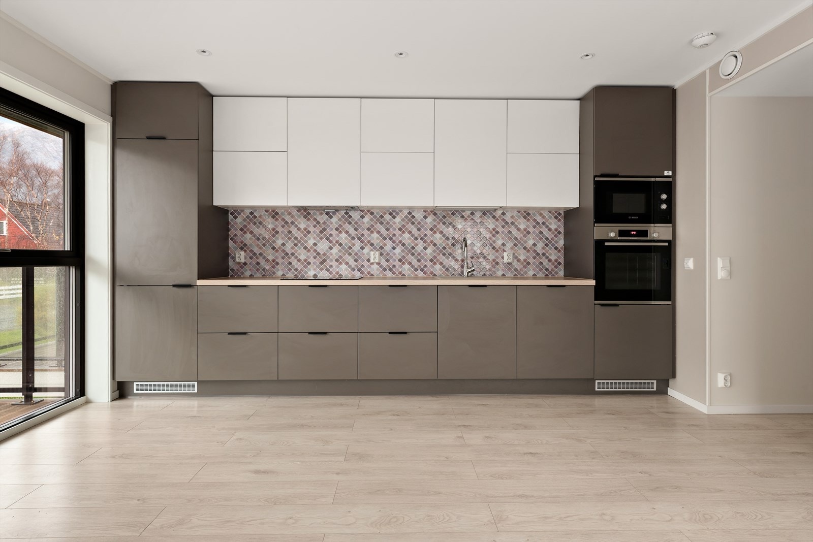 Kjøkkeninnredning i nydelig hvit og bruntoner. Integrerte hvitevarer: Boch kjøl/fryseskap, induction platetopp, komfyr, micro og vaskemaskin. Galleribilde