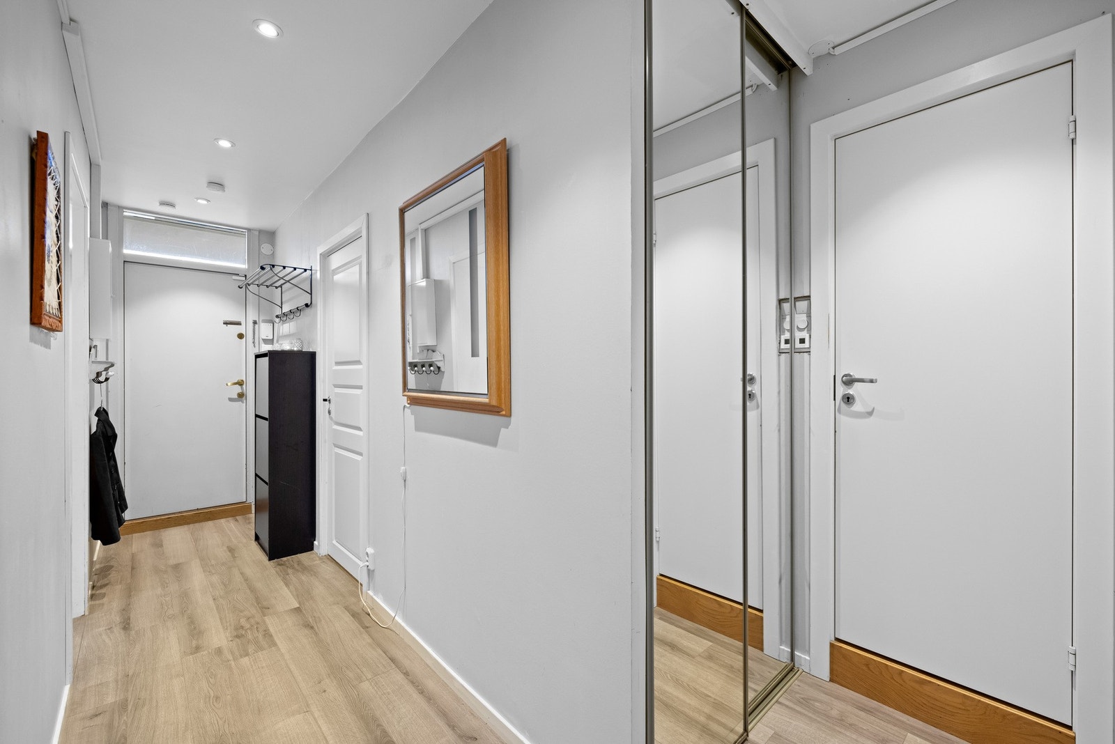 Videre i gangen er det en praktisk skyvedørsgardeobe. Her er det også adkomst til baderommet. Galleribilde