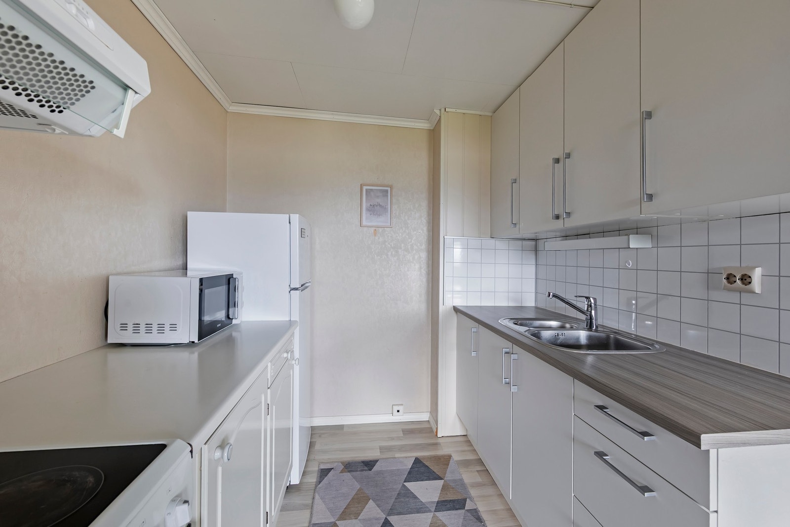 Kjøkken i hybelleilighet har innredning med malte, glatte fronter, takhøye overskap og benkeplate i laminat Galleribilde