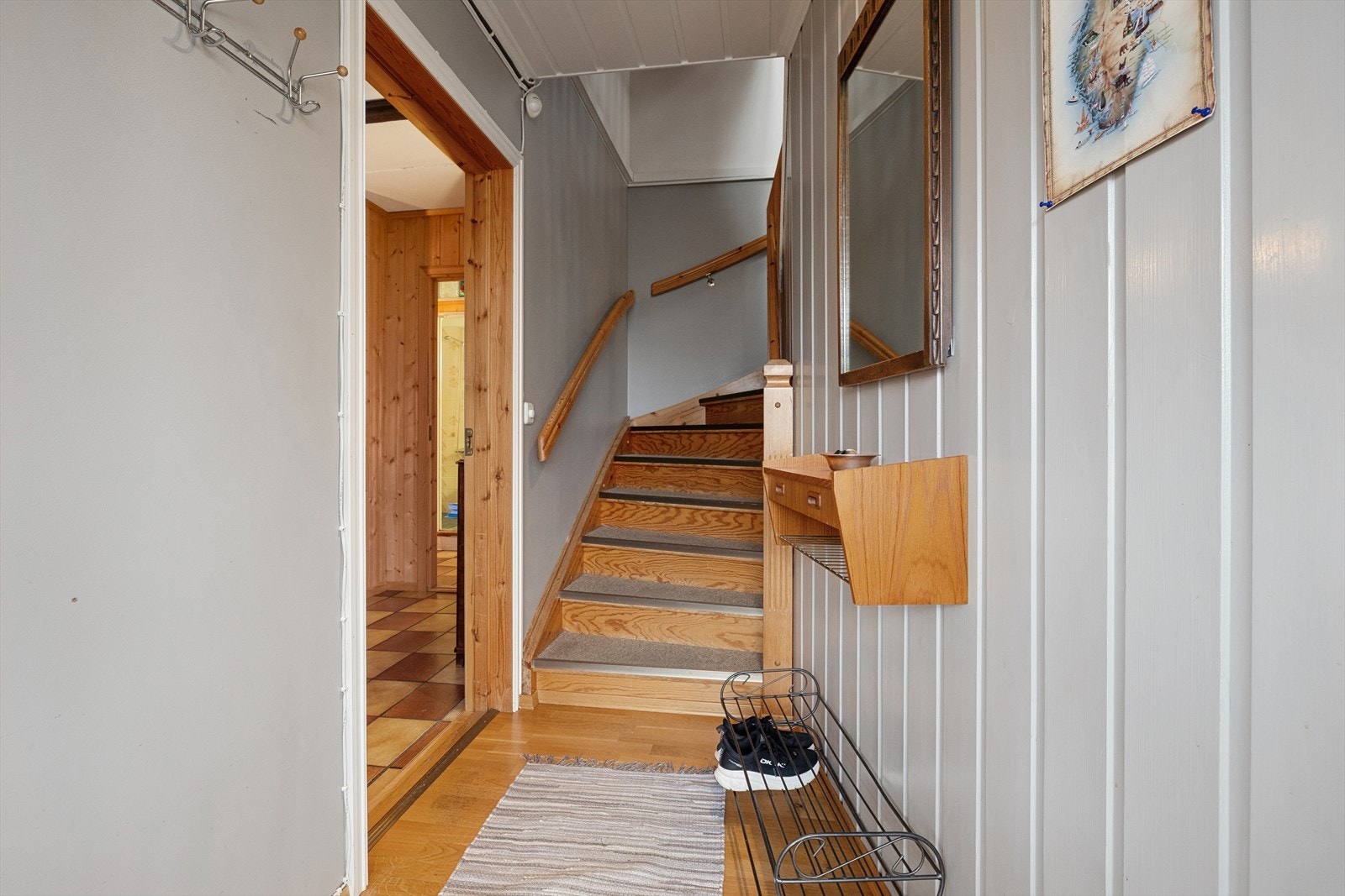 Lakkert tretrapp gir tilgang til boligens andre etasje. Veggene er kledd med panel, og gulvet består av parkett. Galleribilde