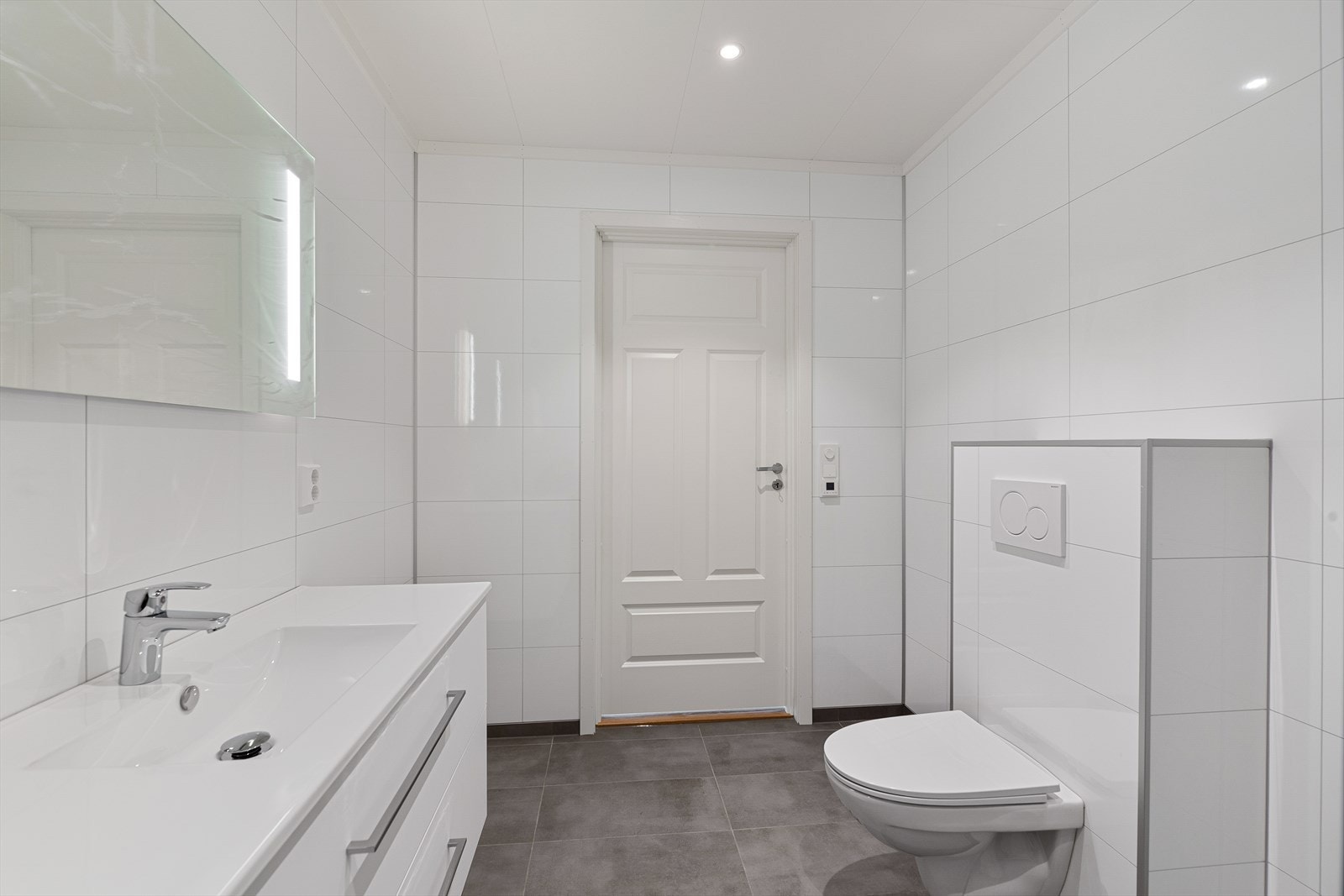 Badet er innredet med baderomsinnredning i hvit utførelse med heldekkende nedfelt servant og rom for diverse oppbevaring i skuffeseksjon og speil med ledbelysning. Galleribilde