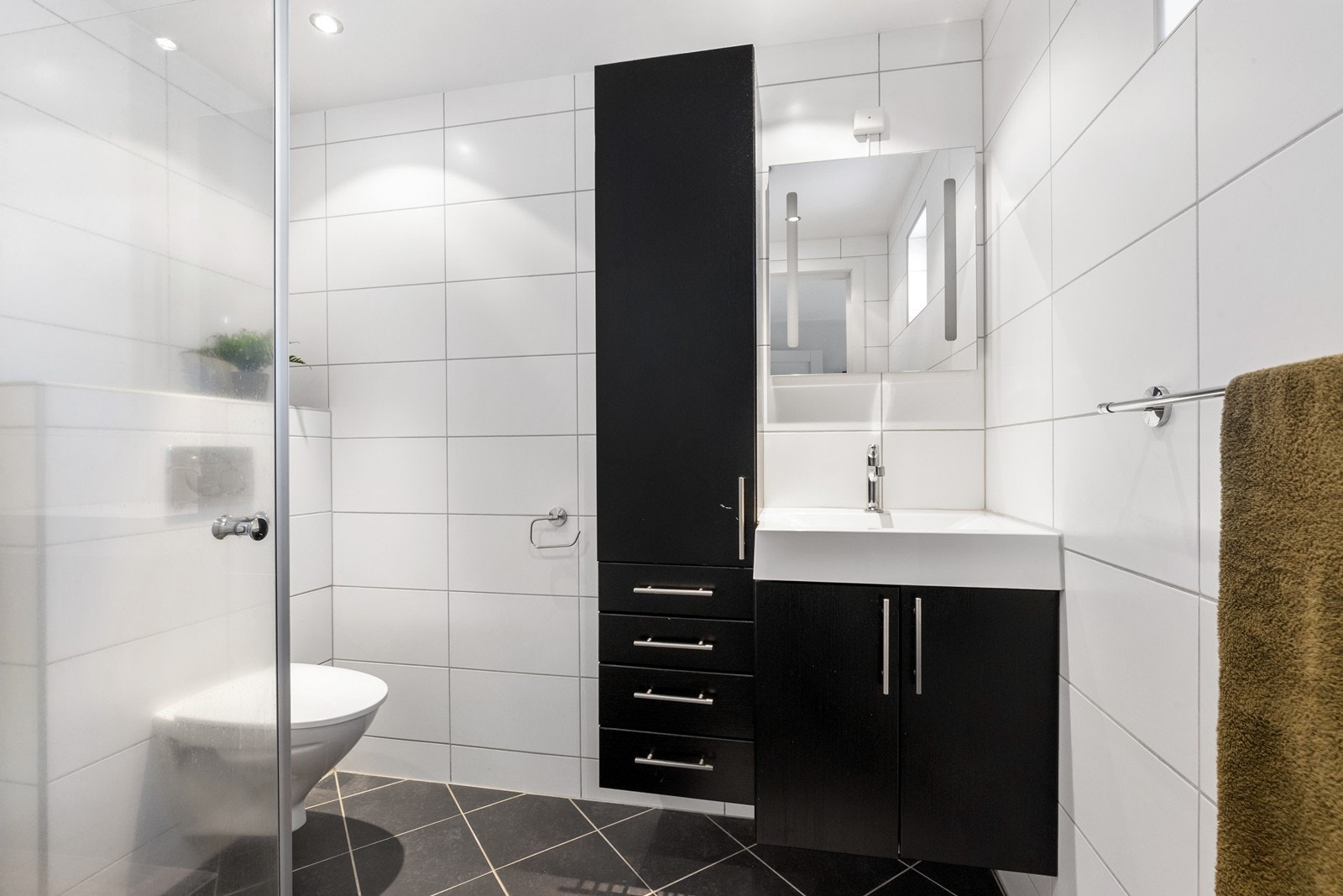 Flislagt bad (1) i tilknytning til soverom. Praktisk utstyrt bad og med dusjhjørne med innfellbare glassdører. Galleribilde