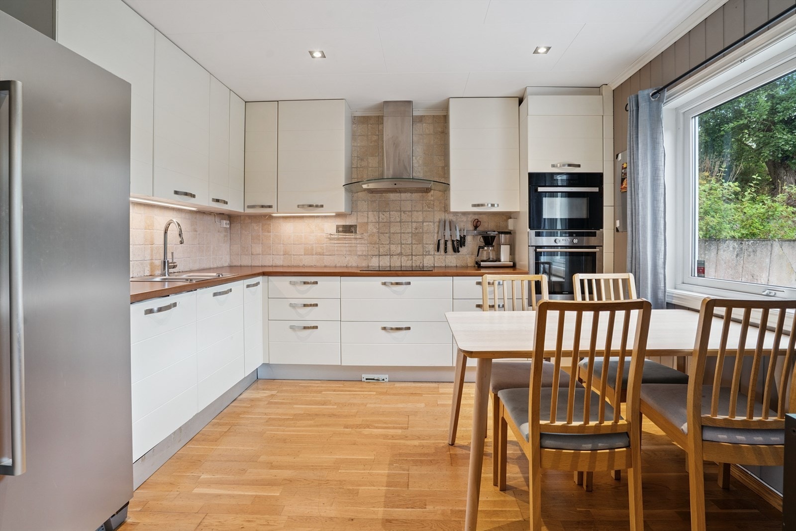 Pent kjøkken med integrerte hvitevarer og frittstående kjøl/fryseskap Galleribilde