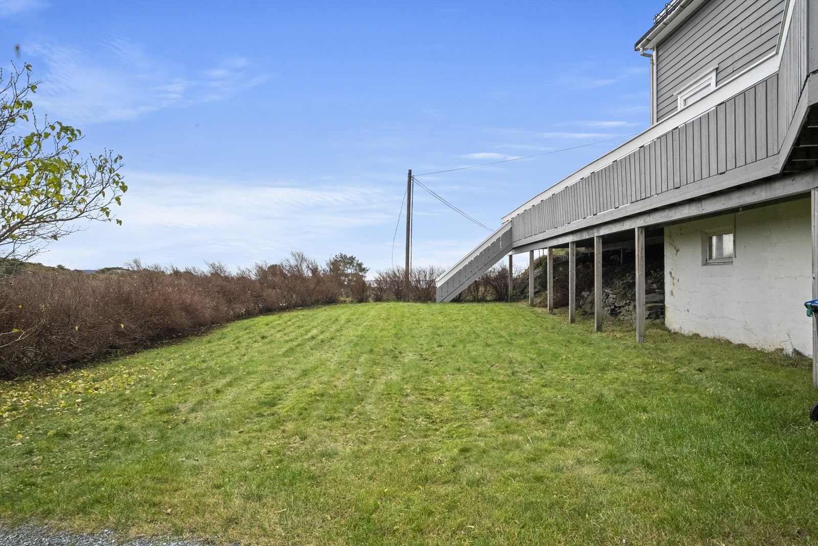 Framfor bustaden er det fint opparbeida hage med flate plenareal og hekk mot veg - adkomst opp til terrassen via trapp Galleribilde