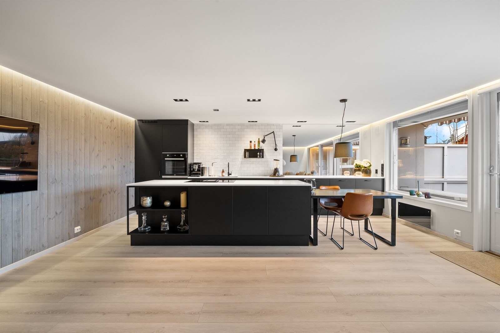 Et stilrent kjøkken med sorte slette fronter og benkeplate av stein Galleribilde