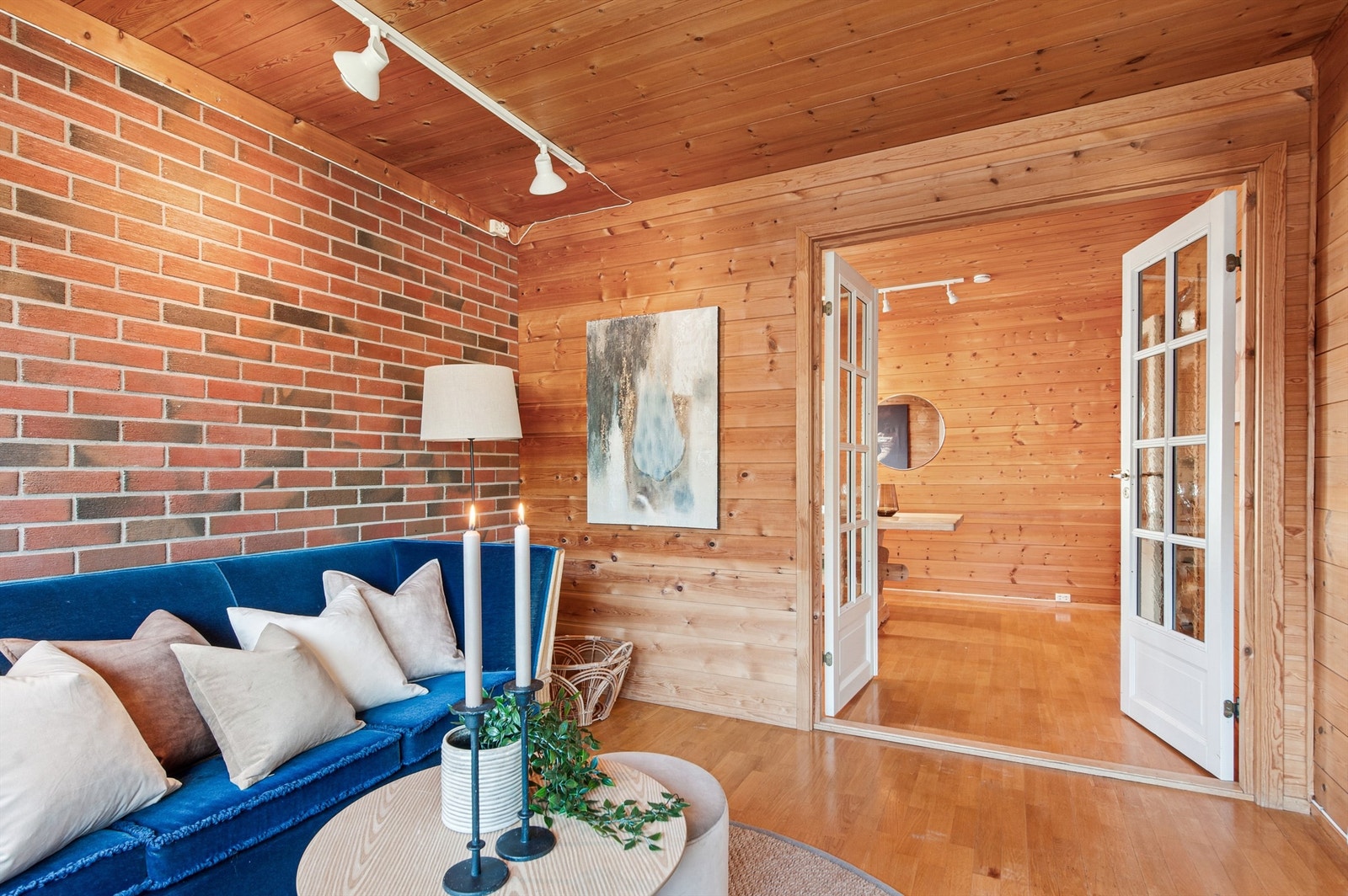 Stue del med lun atmosfære med en kombinasjon av trepanel og sjarmerende teglsteinsvegg. Galleribilde