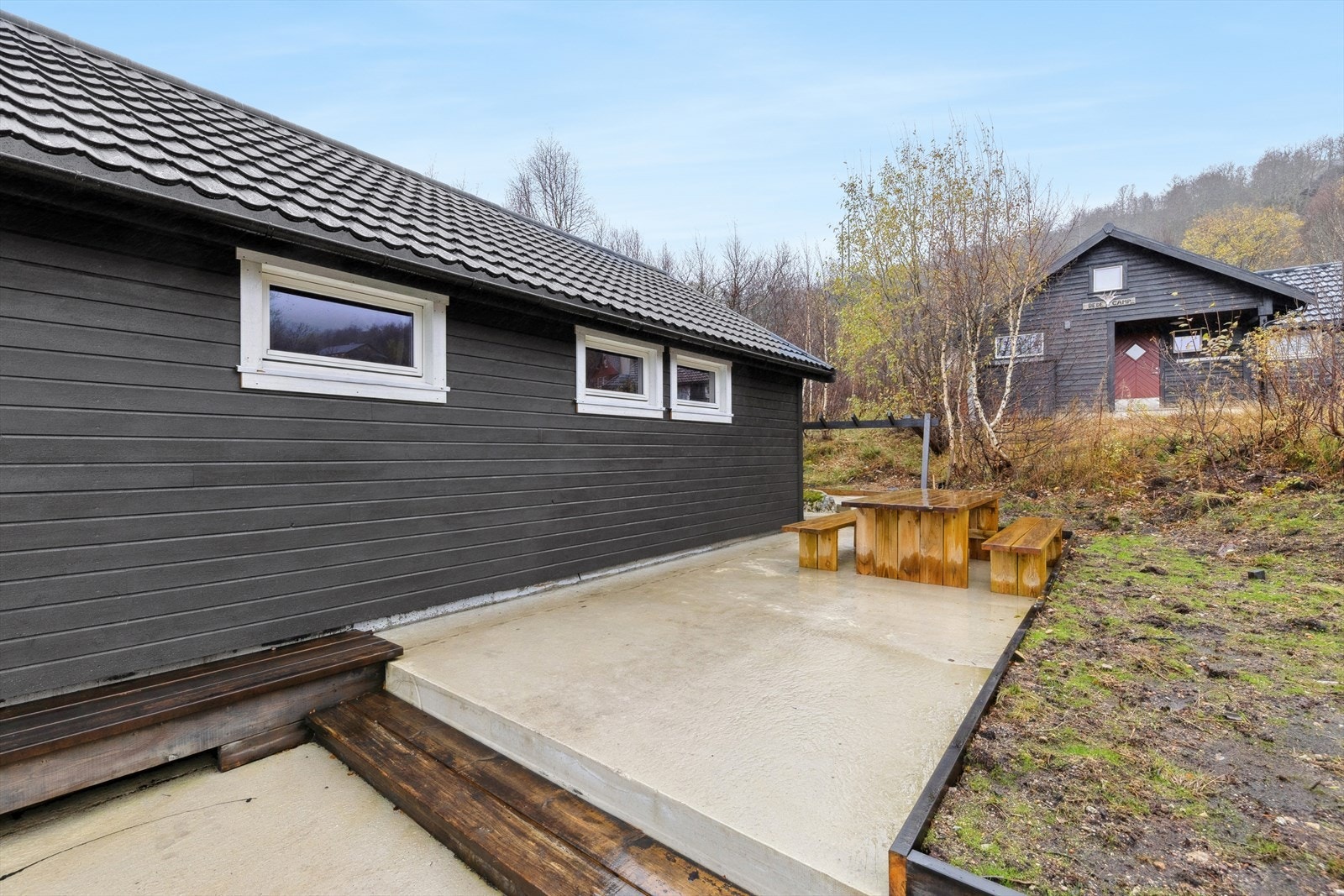 Området rundt hytta er pent opparbeidet med plattinger av betong for minimalt med vedlikehold og en terrasse av tre med utgang fra stuen. Her har man god plass til å møblere i flere soner og flytte seg etter solforholdene. Galleribilde