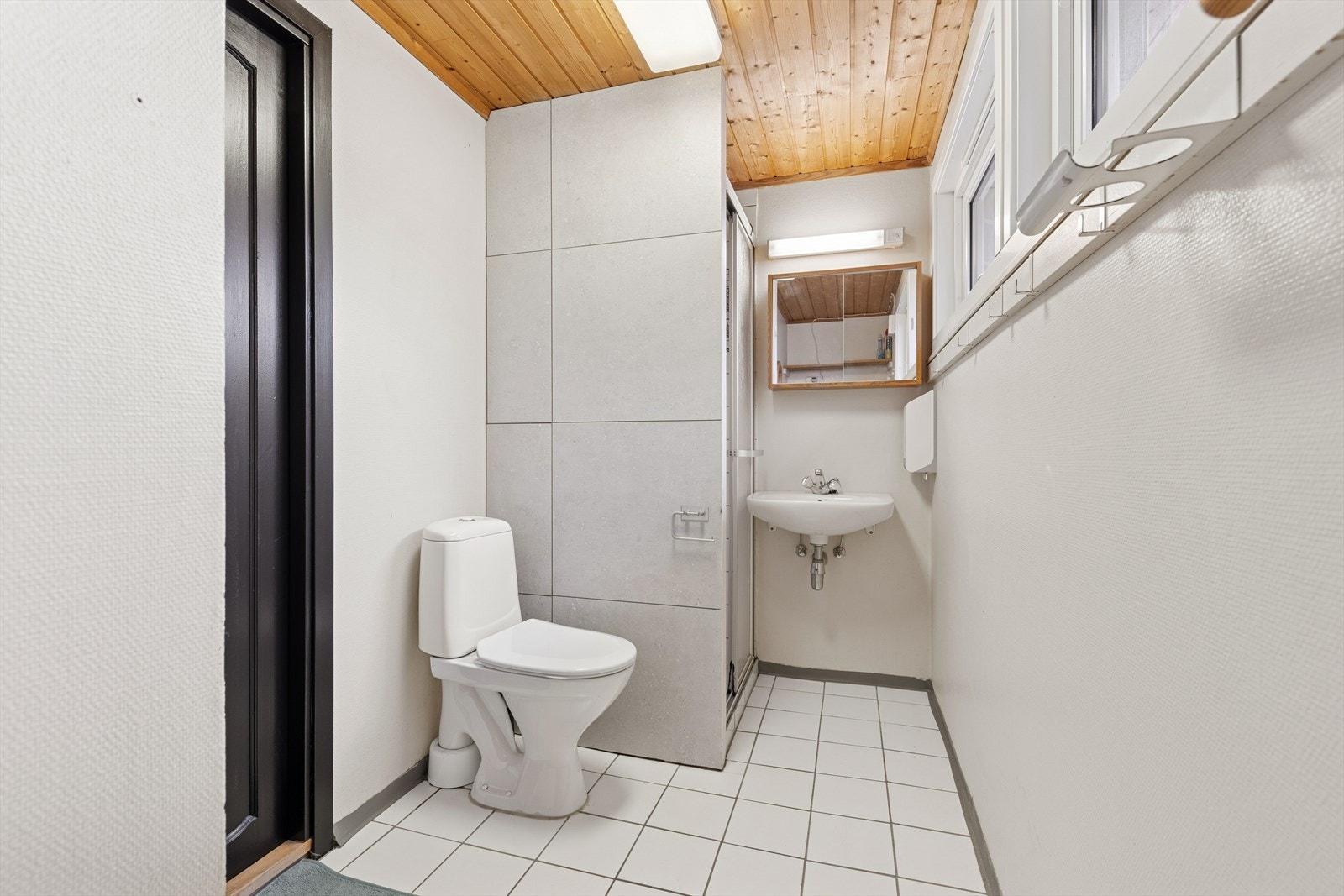 Badet er innredet med lyse fliser på gulvet og en kombinasjon av lyse fliser og lys våtromstapet på vegg. I gulvet har man også varmekabler for ekstra komfort. Galleribilde