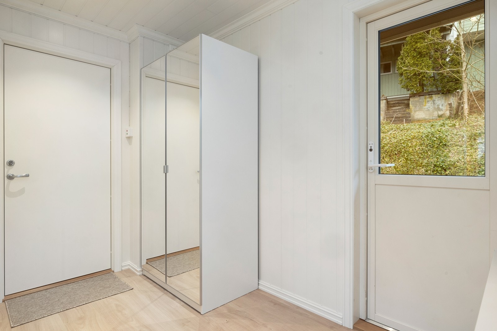 Entré med laminat på gulvet og panel på veggene. God plass til garderobeskap for oppbevaring i gangen. Galleribilde